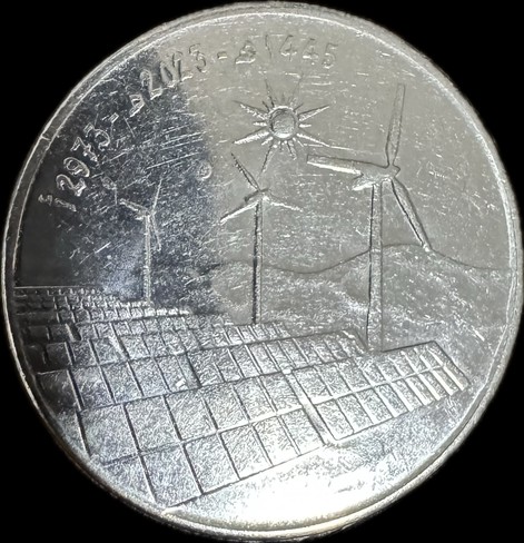 A silver metallic coin (10 Algerian DZD) featuring an engraved design of wind turbines and solar panels under a sun. The surface shows some scratches and wear.
